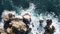 Aerial shot of a rocky shoreline with pounding waves crashing against the large rocks. Royalty Free Stock Photo