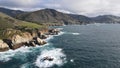 Aerial shot of a rocky shoreline with pounding waves crashing against the large rocks. Royalty Free Stock Photo