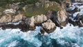 Aerial shot of a rocky shoreline with pounding waves crashing against the large rocks. Royalty Free Stock Photo