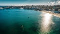 Aerial shot of a sea reflecting sunshine with a cityscape in the background Royalty Free Stock Photo