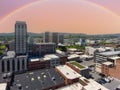 aerial shot of skyscrapers, office buildings, and apartments with lush green trees, mountains, cars on the street, pink sky,