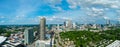 An aerial shot of the skyscrapers and office buildings in the city skyline with miles of lush green trees with cars driving