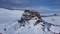 Aerial shot of the sphinx of Bucegi surrounded by mountains in snow, Romania