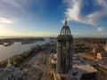 An aerial shot of a stunning sunrise over Mobile Bay with skyscrapers, office buildings, shipping cranes, ships docked