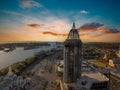 An aerial shot of a stunning sunrise over Mobile Bay with skyscrapers, office buildings, shipping cranes, ships docked