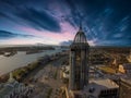 An aerial shot of a stunning sunrise over Mobile Bay with skyscrapers, office buildings, shipping cranes, ships docked