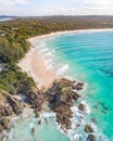 Aerial shot at sunrise over the ocean and white sand beach with swimmers and surfers enjoying summer Royalty Free Stock Photo