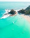 Aerial shot at sunrise over the ocean and white sand beach with swimmers and surfers enjoying summer Royalty Free Stock Photo