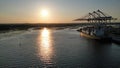 Sunset at river delta and container ship silhouette at shipping port