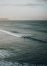 Aerial shot of a surfer on the wavy sea or lake on the background of mountains and foggy sky Royalty Free Stock Photo