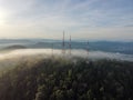 Aerial shot of telecommunication towers on the top of a hill on a foggy day Royalty Free Stock Photo