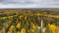 Aerial shot of a tower surrounded by autumn trees in a forest, Haanja, Munamagi, Estonia