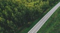 Aerial shot of two lane highway through green poplar tree woodland from drone pov