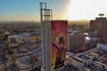 an aerial shot of a Willy Wonka billboard along Hollywood blvd at sunset with hotels and office buildings in the city skyline