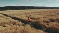 Aerial tracking shot of a young athletic man cycling fast along rural field pathway