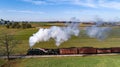 Aerial Side View of a Steam Freight Train Traveling Thru Farmlands Blowing Smoke