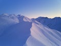 Aerial of snowy mountain slopes full of powder for freeride at ski resort on winter sunrise. Mountains range of Royalty Free Stock Photo