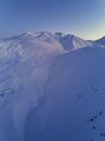 Aerial of snowy mountain slopes full of powder for freeride at ski resort on winter sunrise. Mountains range of Royalty Free Stock Photo