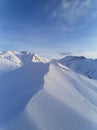 Aerial of snowy mountain slopes full of powder for freeride at ski resort on winter sunrise. Mountains range of Royalty Free Stock Photo