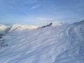 Aerial of snowy mountain slopes full of powder for freeride at ski resort on winter sunrise. Mountains range of Royalty Free Stock Photo