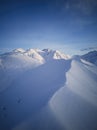 Aerial of snowy mountain slopes full of powder for freeride at ski resort on winter sunrise. Mountains range of Royalty Free Stock Photo