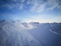 Aerial of snowy mountain slopes full of powder for freeride at ski resort on winter sunrise. Mountains range of Royalty Free Stock Photo