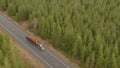 AERIAL: Speeding big rig transports heavy logs down an empty asphalt highway. Royalty Free Stock Photo