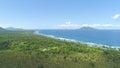 AERIAL: Stunning ocean waves approach the palm tree plantation on sunny island.