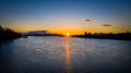 Aerial of sun setting over river bridge in the background