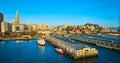 Aerial sunrise lighting over boats docked at piers with Transamerica Pyramid and Coit Tower