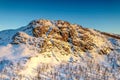 AERIAL: Sunset golden light over Norwegian snowy winter mountains with birch and pine trees, early spring, calm blue skies. Royalty Free Stock Photo