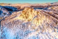 AERIAL: Sunset golden light over Norwegian snowy winter mountains with birch and pine trees, early spring, calm blue skies. Royalty Free Stock Photo