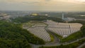 Aerial: Sunset light over panels on solar farm on edge of city Royalty Free Stock Photo