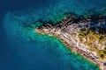 Aerial top down shot of rocky shore and turquoise water of aegean sea