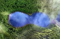 Aerial top down view of beautiful green waters of lake. Birds eye view of scenic emerald lake surrounded by pine forests. Clouds