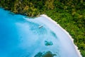 Aerial top down view of boat moored at secluded white sand beach with coconut palm trees and surreal turquoise blue Royalty Free Stock Photo