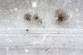 Aerial top down view at a colorful rainbow umbrella in the middle of a snow covered landscape at snowfall and some trees