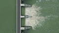 Aerial: top down view of dam releasing water, water discharge downstream. Royalty Free Stock Photo