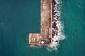 Aerial top down view of old concrete pier or breakwater with lighthouse and emerald sea water with waves Royalty Free Stock Photo
