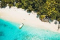 Aerial top down view of paradise beach with coconut trees and lonely tourist boat in turquoise shallow lagoon water Royalty Free Stock Photo