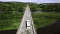 Aerial top down view of small road bridge across the river in rural area. Clip. Cars driving on the bridge and green Royalty Free Stock Photo