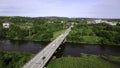 Aerial top down view of small road bridge across the river in rural area. Clip. Cars driving on the bridge and green Royalty Free Stock Photo