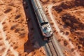 Aerial top-down view of a train traveling through the vast, empty desert, leaving behind a long trail of dust Royalty Free Stock Photo