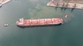 Aerial top down view of Tug boats assisting big cargo ship. Large cargo ship enters the port escorted by tugboats Royalty Free Stock Photo