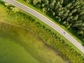 Aerial top down view of two-lane road with pine tree forests on one side, and green lake on the other. Beautiful summer scenery in Royalty Free Stock Photo