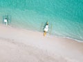 Aerial top down view of white sand beach with a traditional philippine boats beached on it