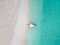 Aerial top down view of white sand beach with a traditional philippine boats beached on it