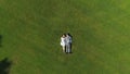 AERIAL TOP DOWN: Young loving parents to be lying down on grass on sunlit day Royalty Free Stock Photo