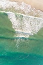 aerial top drone view of a wave breaking on the shore of a beach, vertical image Royalty Free Stock Photo