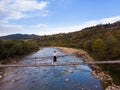 Aerial top view of woman traveller on wooden bridge over mountains river